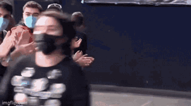 a group of people wearing face masks are standing in a line applauding .