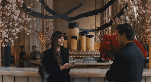 a man is holding a bouquet of red flowers and a woman is holding a cell phone