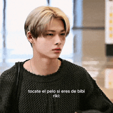 a young man wearing a black sweater with the words tocate el pelo si eres de bibi riki written above him
