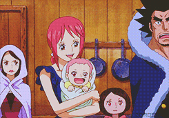 a woman is holding a baby in her arms while a man looks on