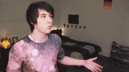 a young man wearing a galaxy shirt is standing in a room with his arms outstretched