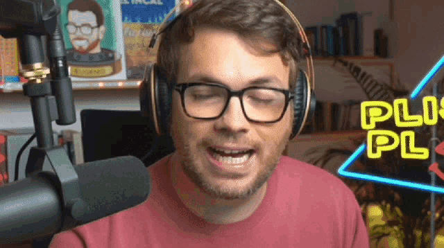 a man wearing glasses and headphones stands in front of a microphone with a neon sign that says plus pl