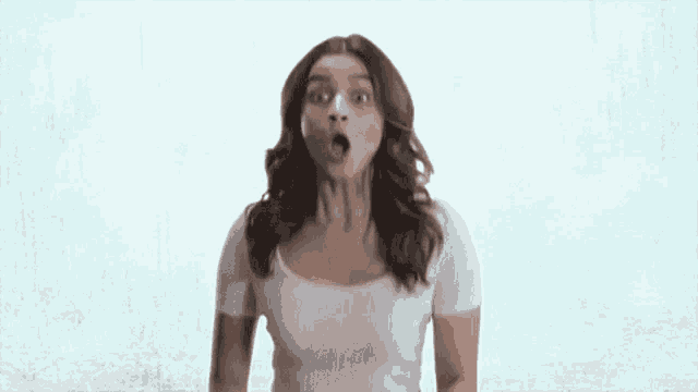 a woman is making a surprised face while wearing a white shirt .