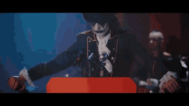 a man in a clown costume is standing at a podium with a microphone in front of him .
