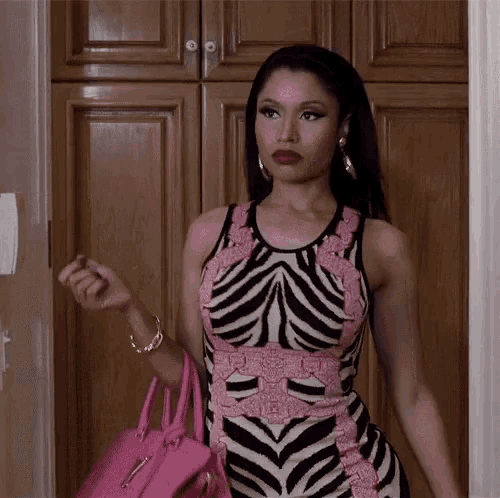 a woman in a zebra print dress is holding a pink purse and looking at the camera .