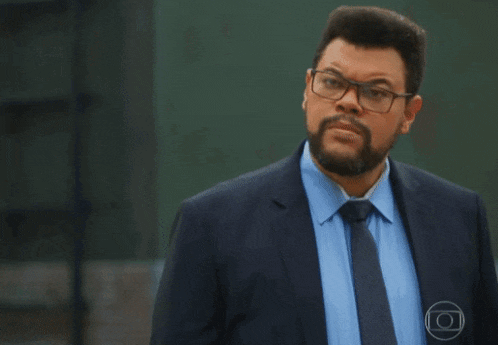 a man with a beard wearing glasses and a blue suit
