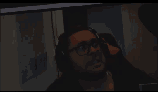 a man wearing glasses and headphones is looking at a computer screen