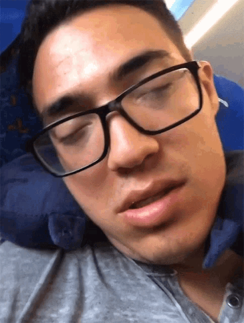 a man wearing glasses is sleeping on a pillow