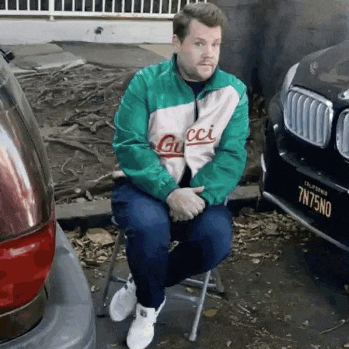 a man in a gucci jacket sits on a chair