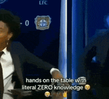 a man in a suit and tie is holding his hands on the table with literal zero knowledge .