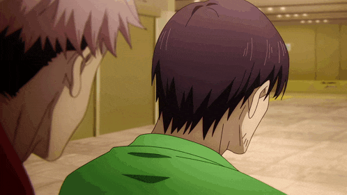 a man in a green shirt is looking at another man in a red shirt