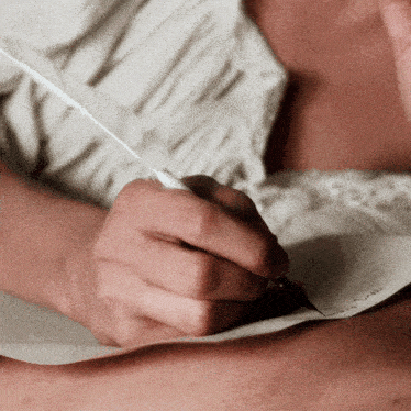a close up of a person 's hand writing with a feather pen