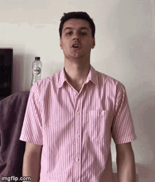 a man wearing a pink and white striped shirt is making a funny face