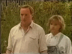 a man and a woman are standing next to each other in front of a field .