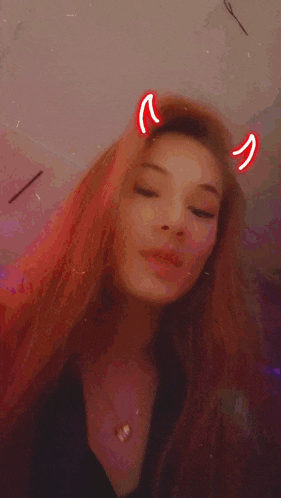 a woman with long hair and devil horns on her head is making a funny face .