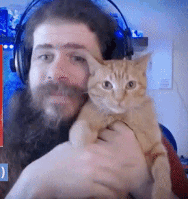 a man with headphones is holding a cat in his arms