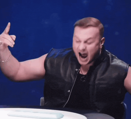 a man in a leather vest is holding something in his hands and screaming