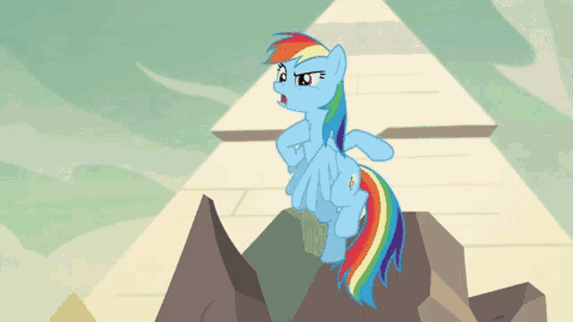 a cartoon pony with a rainbow mane is standing on a rock near a pyramid