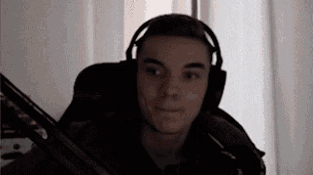a man wearing headphones is sitting in a chair and smiling .