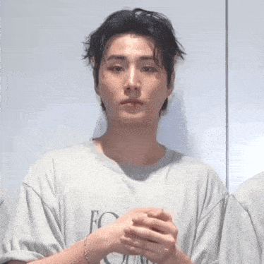 a young man wearing a grey t-shirt with the letter e on it