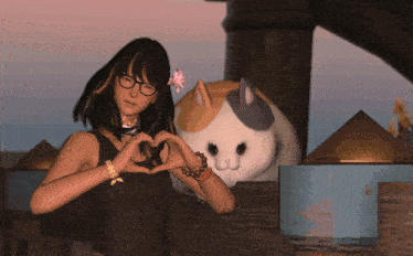 a woman is making a heart shape with her hands next to a stuffed cat
