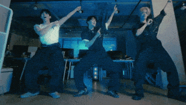 three men are dancing in a dark room