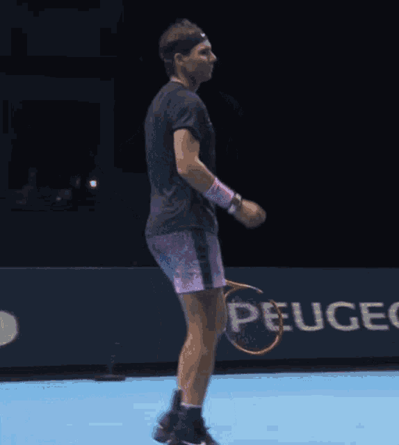 a man holding a tennis racquet stands in front of a sign that says eugene