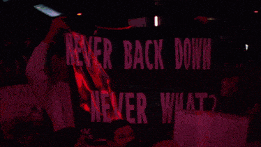 a crowd of people holding signs that say never back down and never what