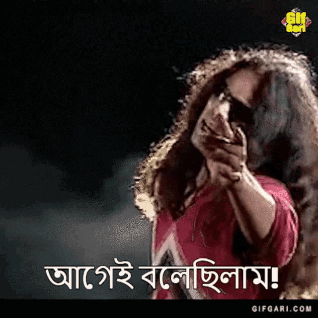 a woman in a red shirt is holding a gun in her hand and making a funny face .
