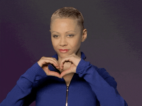 a woman in a blue jacket is making a heart with her hands