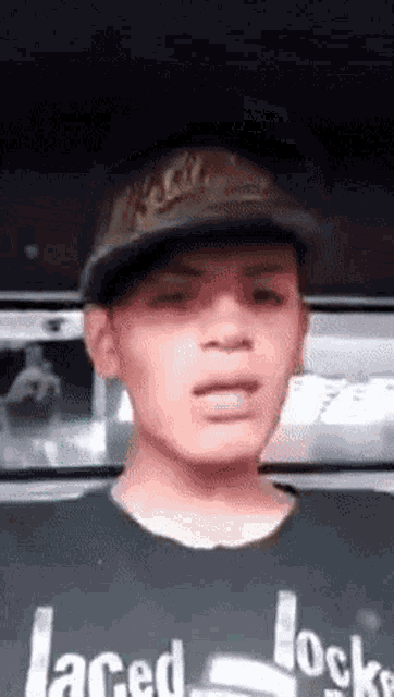 a man wearing a hat and a black shirt that says laced locks