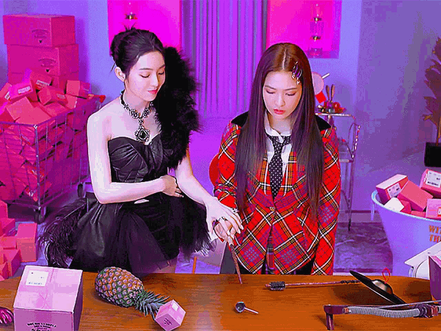 two women are standing next to each other in front of a table with a pineapple and a box that says welcome