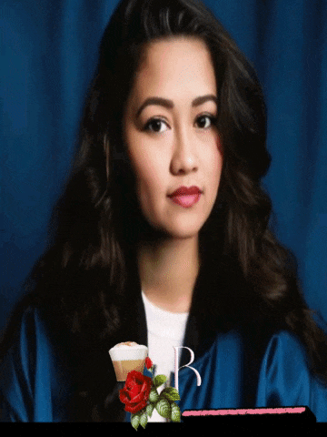 a woman in a graduation cap and gown stands in front of a blue curtain with the word be on it