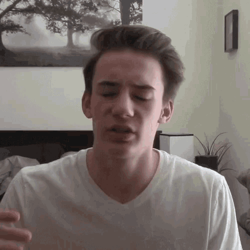 a young man wearing a white t-shirt is making a funny face