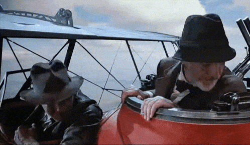 two men in hats are sitting in a plane