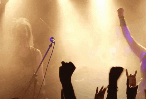 a woman singing into a microphone with a crowd behind her