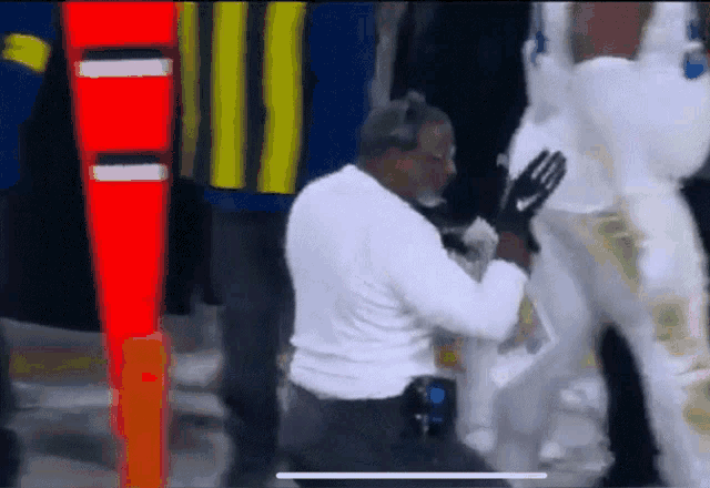 a man in a white shirt is kneeling down next to a man in white pants