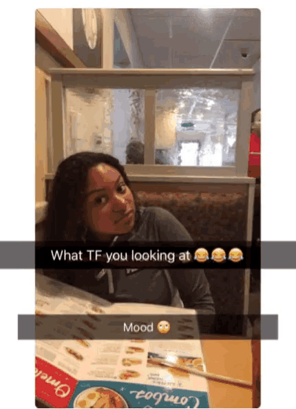 a snapchat of a woman sitting at a table with the caption what tf you looking at and mood
