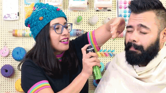 a woman spraying something on a man 's face with the word geek visible