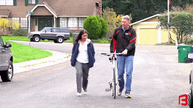 a man and a girl are walking down a street with the letter b on the side of the road
