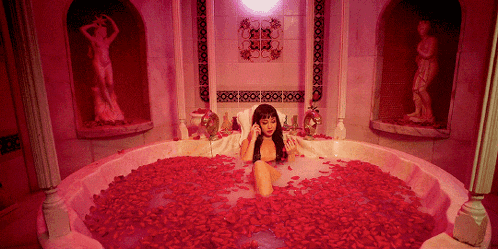 a woman is laying in a bathtub filled with red rose petals