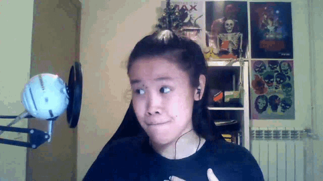 a girl stands in front of a microphone with a poster on the wall that says max on it