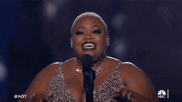 a woman is singing into a microphone with her hands in the air .