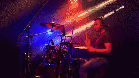 a man is playing drums in front of a microphone in a dark room