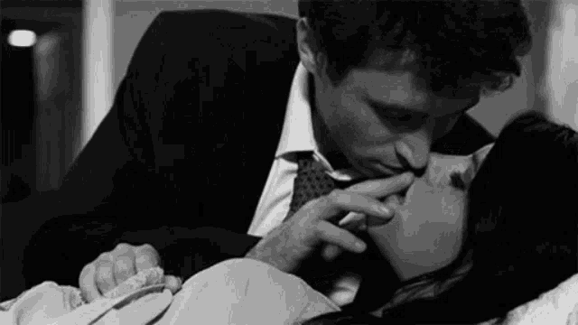 a man in a suit and tie is kissing a woman on the lips .