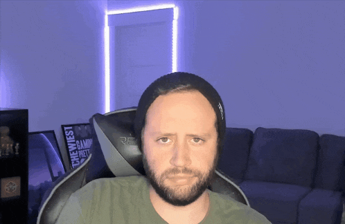 a man with a beard is sitting in a chair with a sign that says the west