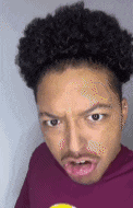 a man with curly hair is making a funny face while wearing a purple shirt .