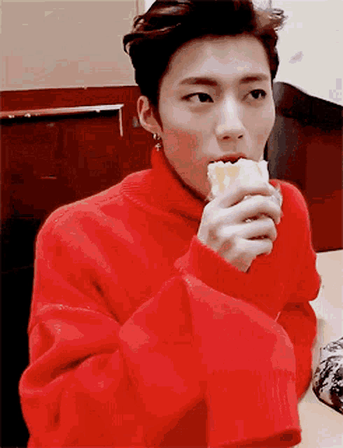 a man in a red sweater is eating a piece of food