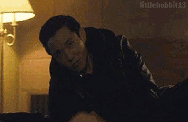 a man in a leather jacket is laying on top of another man in a room .