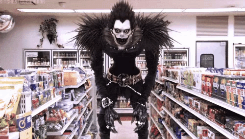 a man in a black costume is standing in a grocery store .